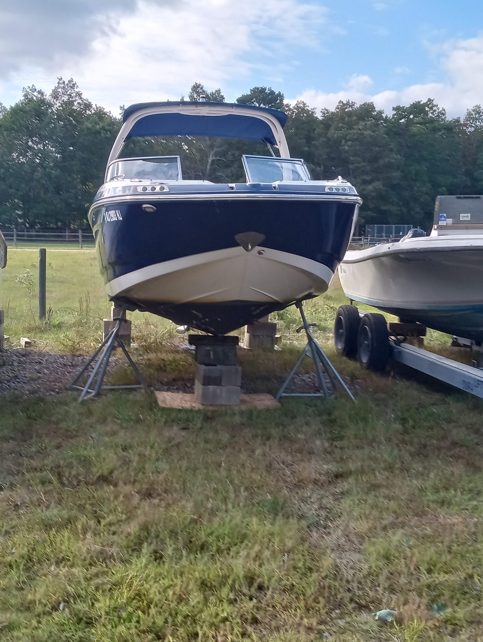 A boat is sitting on a trailer in a grassy field.