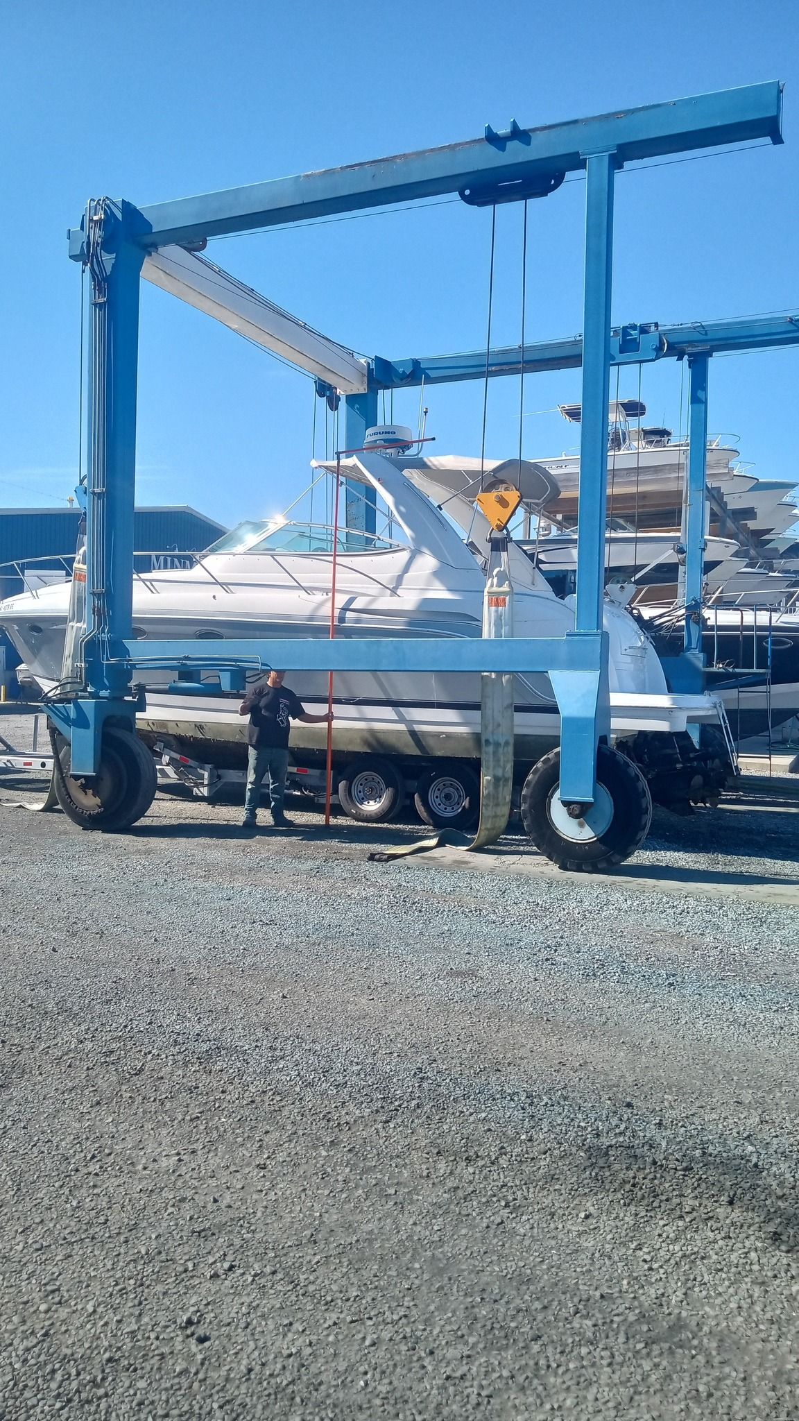A boat is being lifted by a crane in a marina.