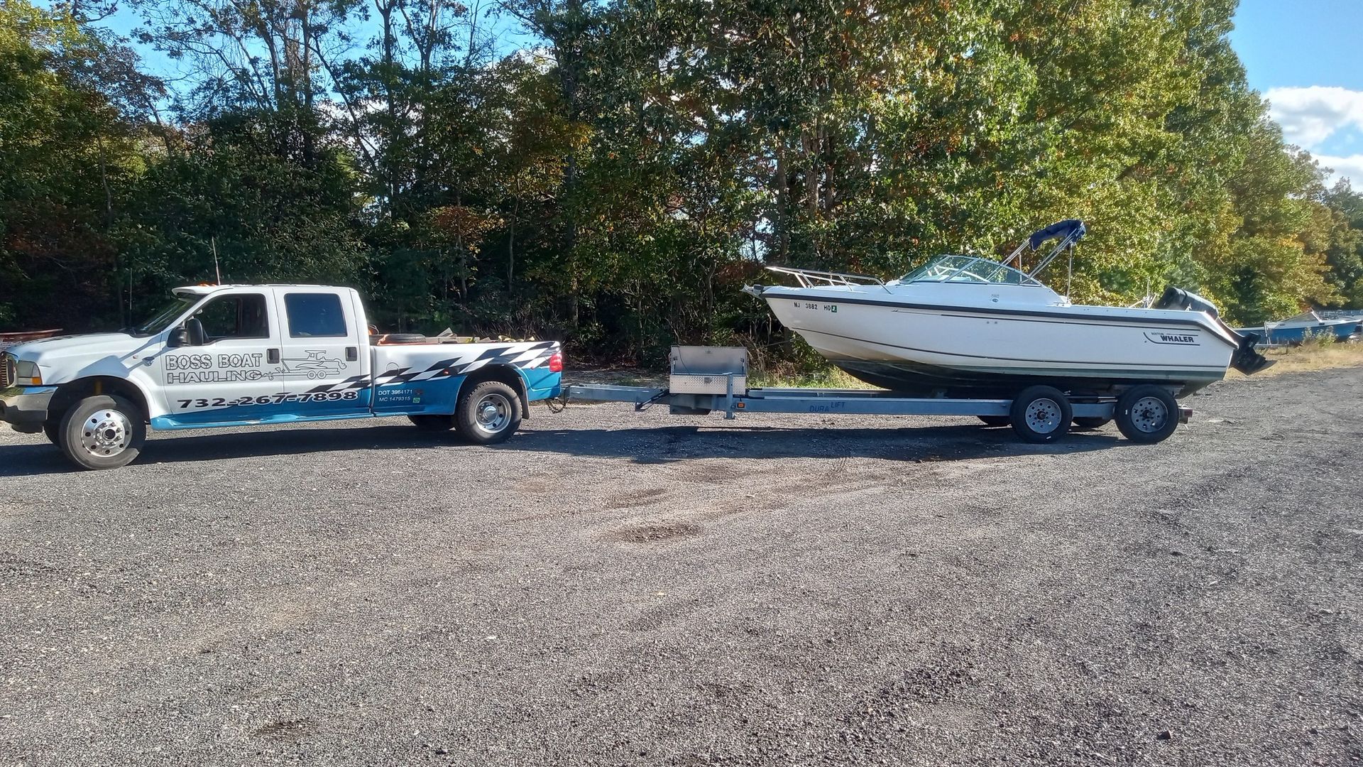 A white truck is towing a boat on a trailer.