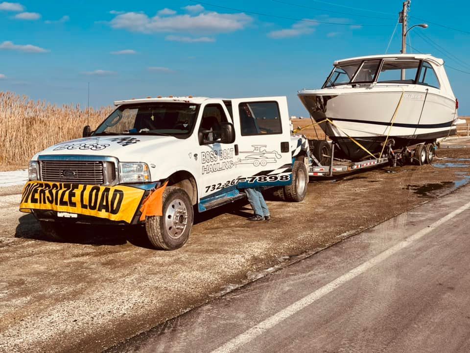 A tow truck is towing a boat down the road.