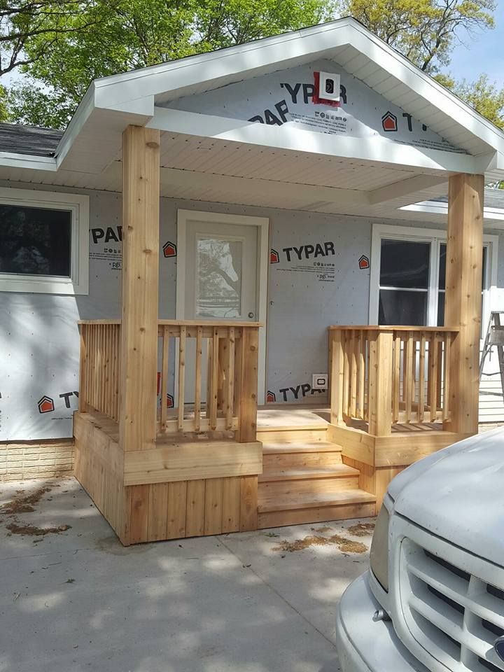 A white truck is parked in front of a house with a porch.