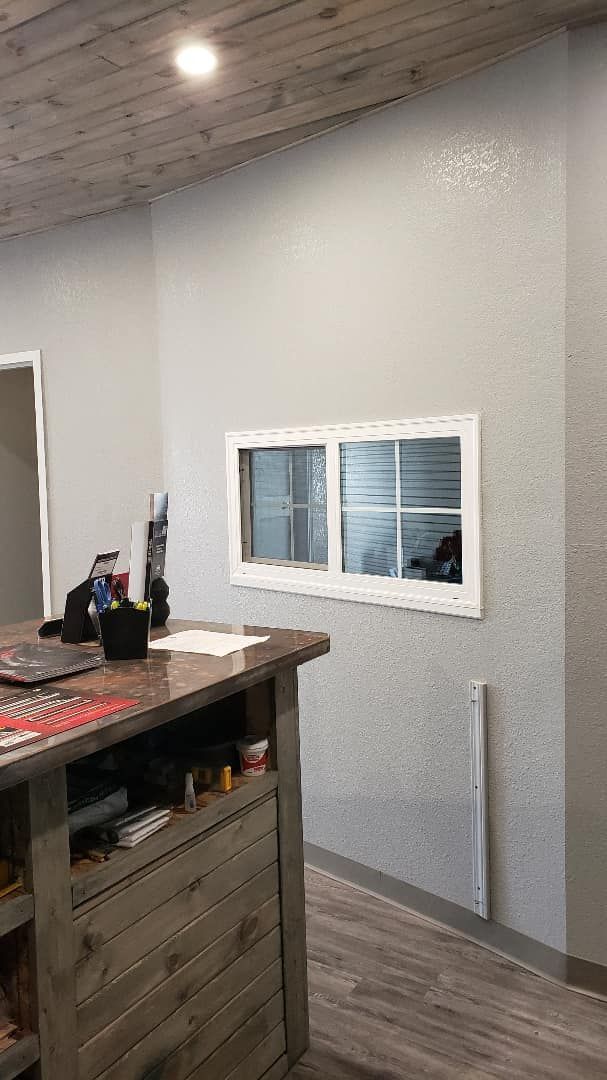 A room with a counter and two windows on the wall.