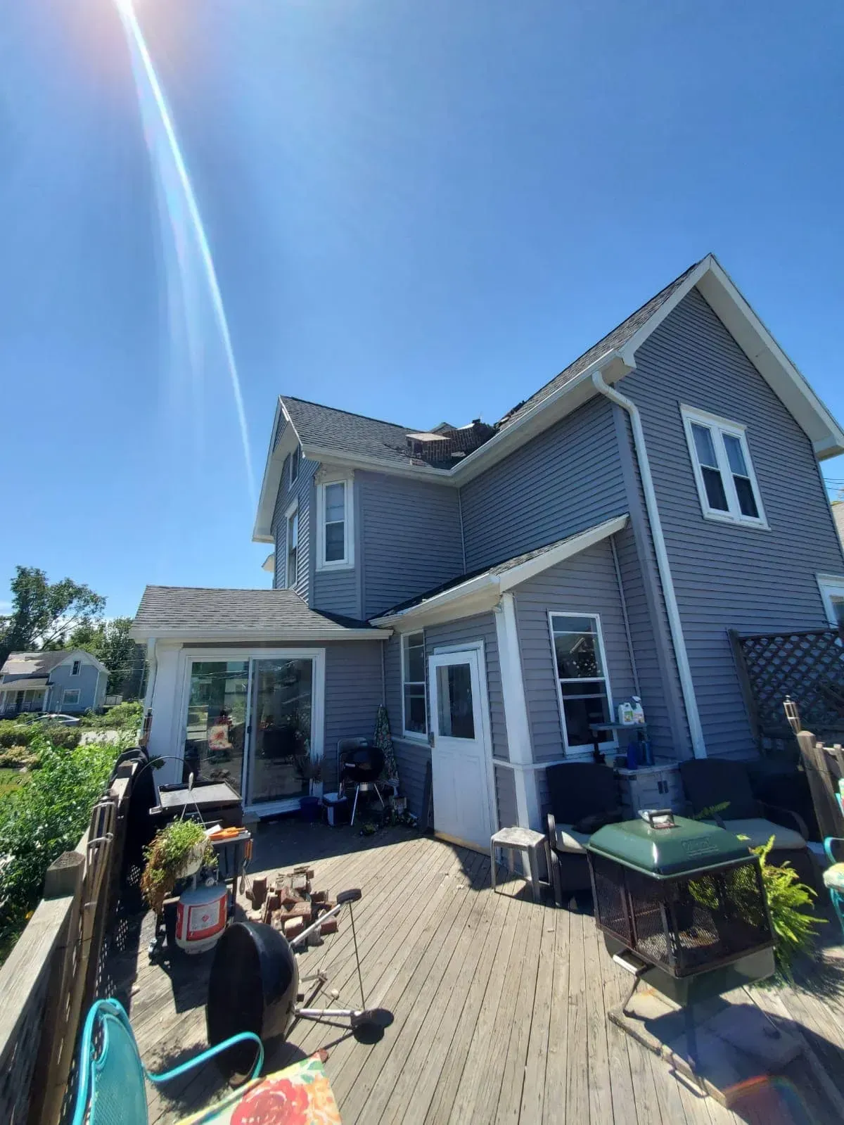 The back of a house with a deck and a grill.