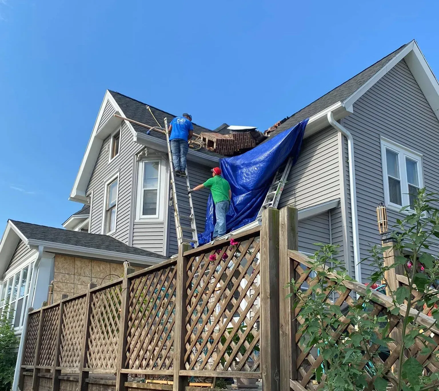 Two men are working on the roof of a house.