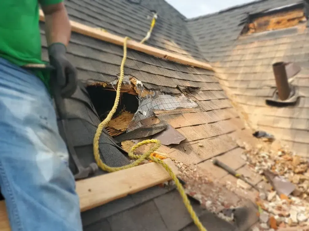A man in a green shirt is working on a roof.