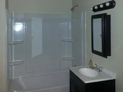 A bathroom with a sink , tub , shower and mirror.