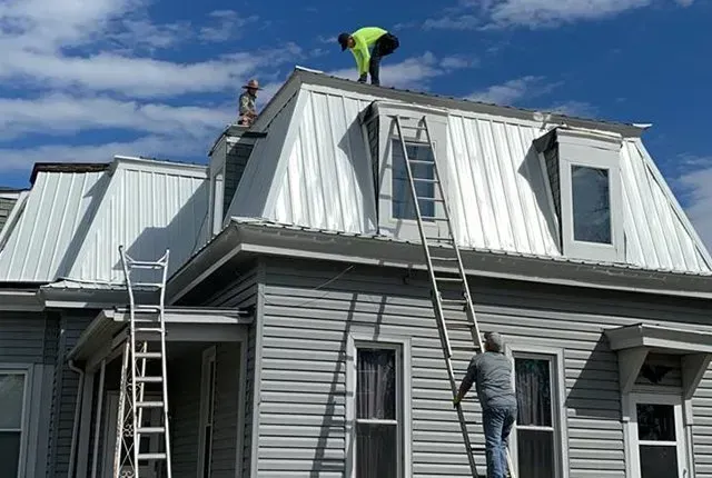Two men are working on the roof of a house.