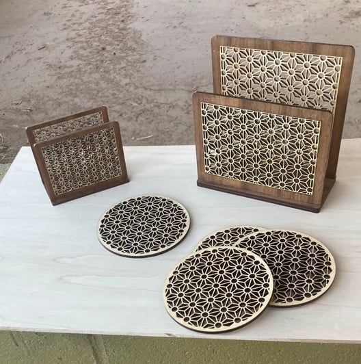 Wooden coaster and holder set with decorative floral cutouts on a light surface.