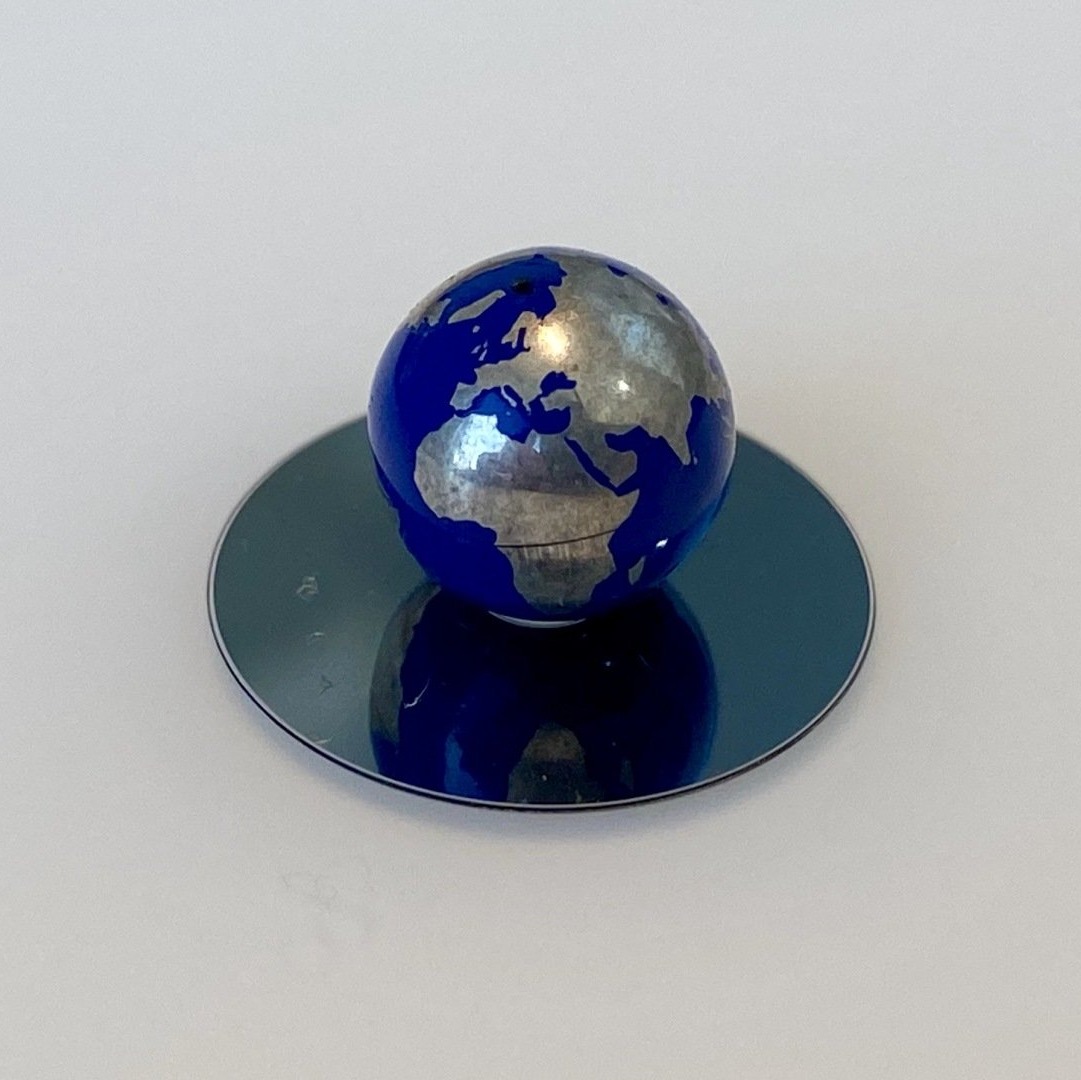 A blue globe on top of a silver plate.