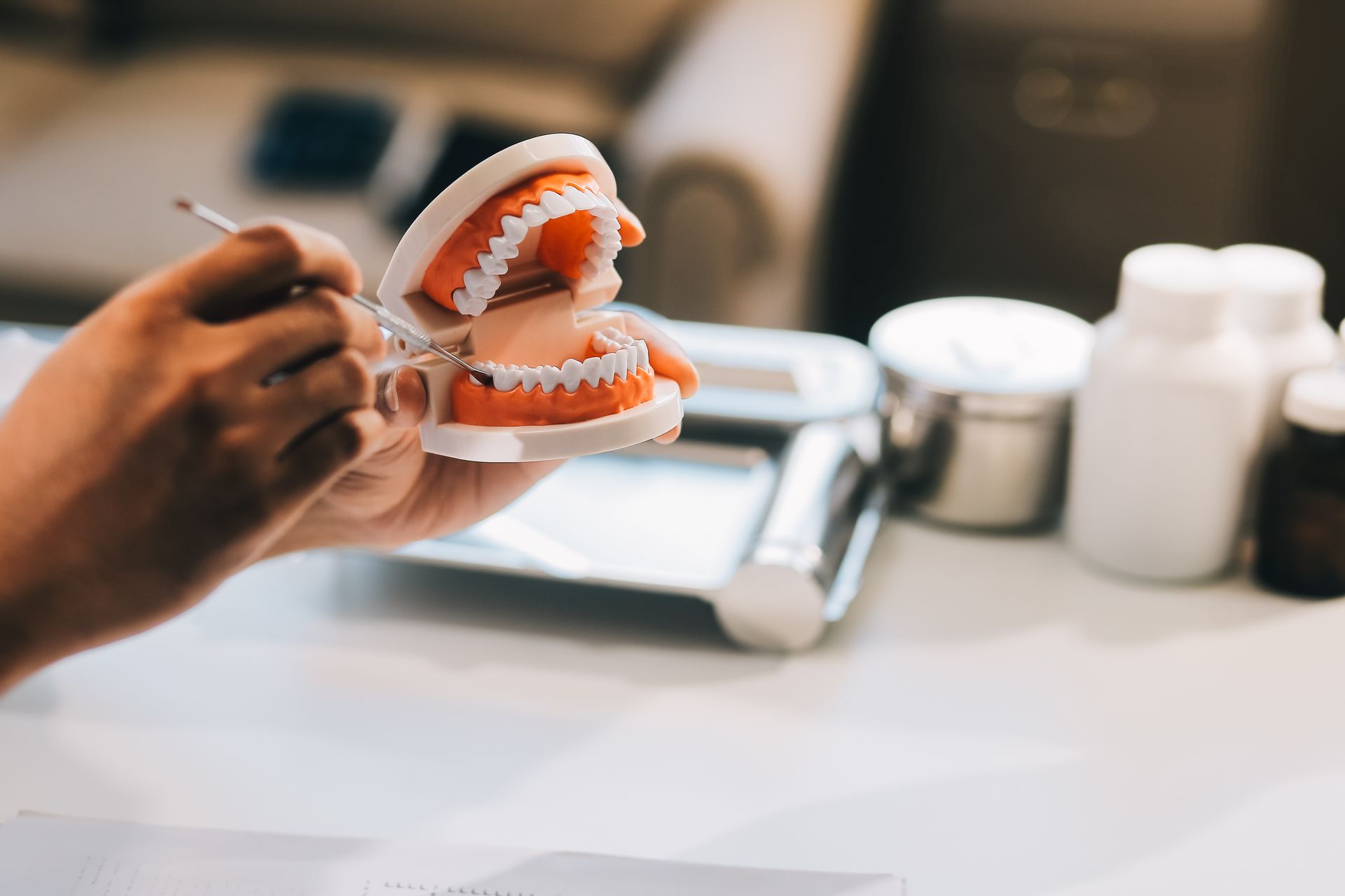 Close-up of a professional inspecting high-quality dentures with a metal dental tool. Close-up of a professional inspecting high-quality dentures with a metal dental tool.