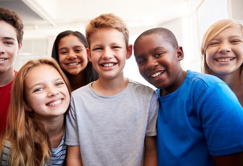 A group of young people are posing for a picture together and smiling.