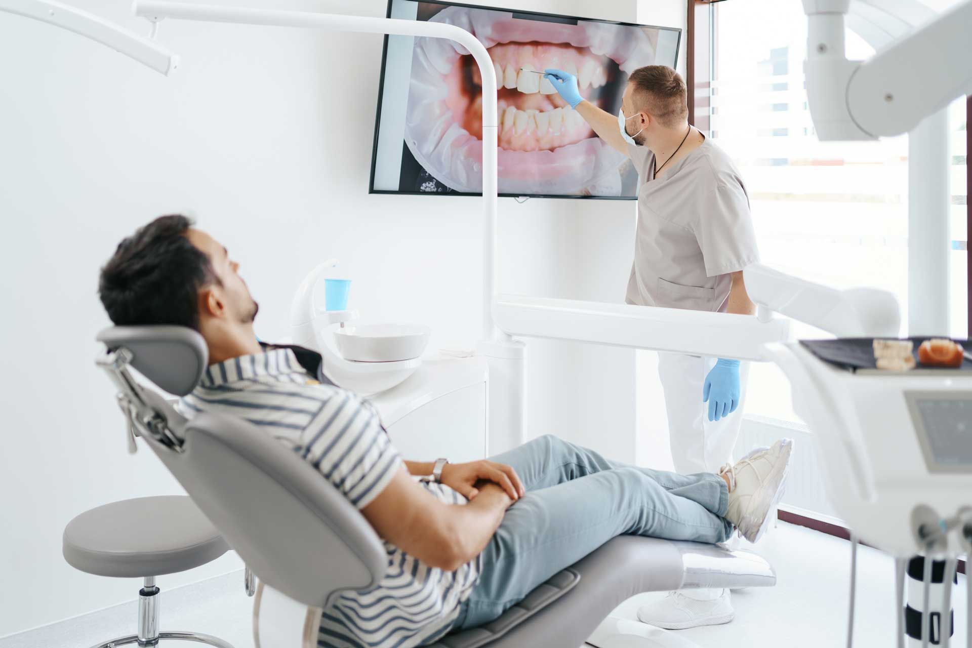 The dentist is explaining the teeth image on the screen.