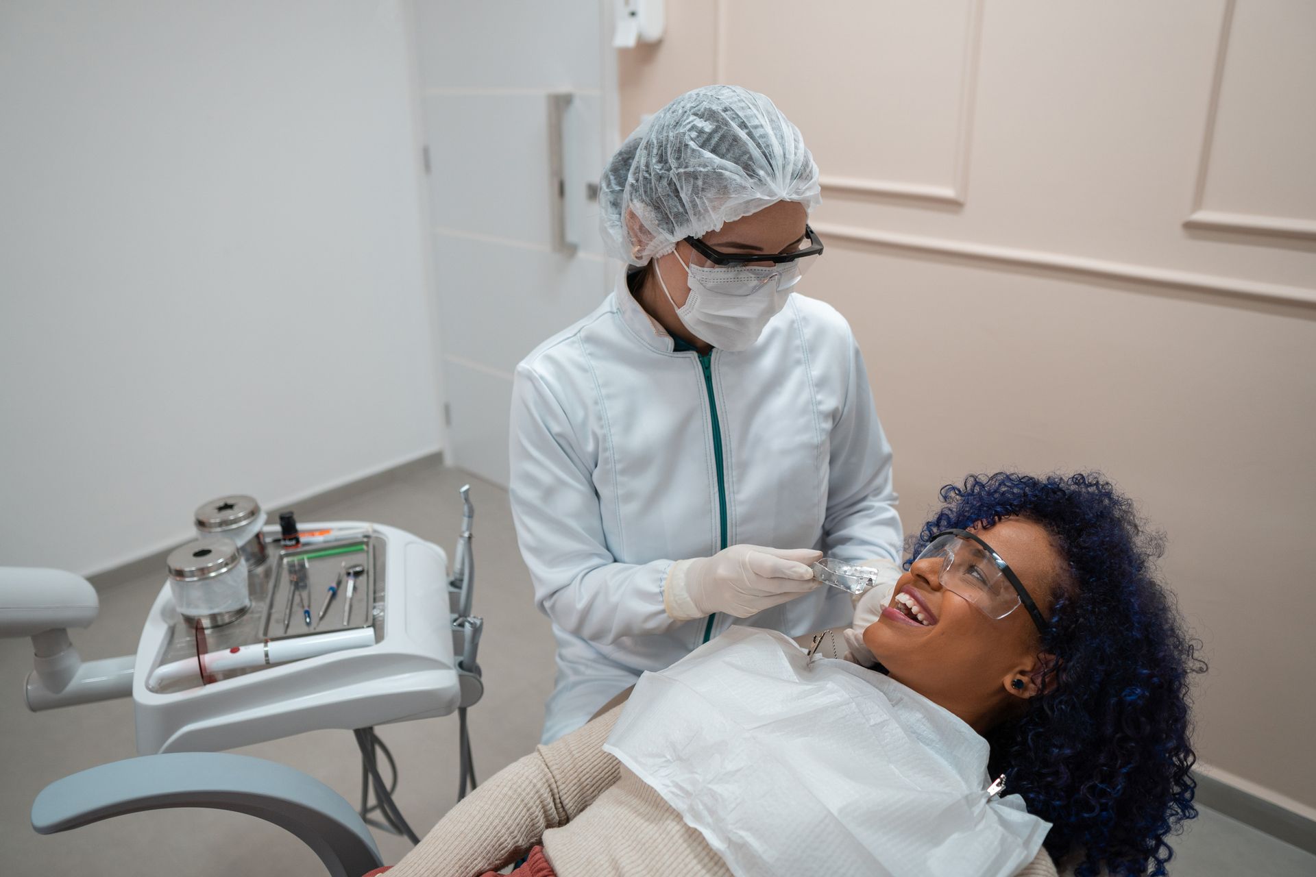 A woman smiling in a dental chair while receiving a check-up from a general dentist.