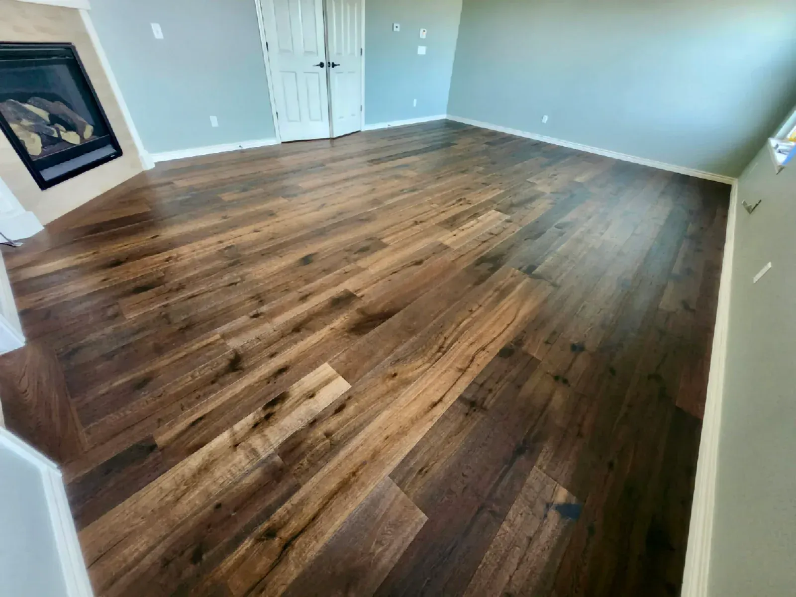 Dark wood flooring in a room with a fireplace and closed white doors. Blue-gray walls.