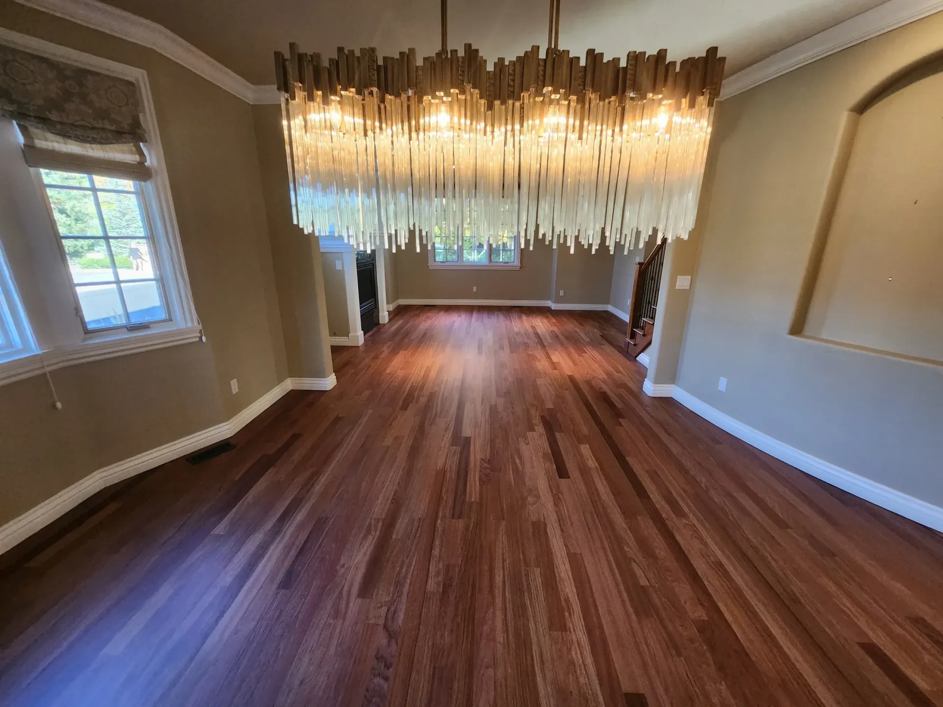 Dining room with hardwood floor, large chandelier, and windows.