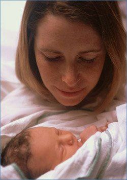 A woman is holding a newborn baby in her arms.
