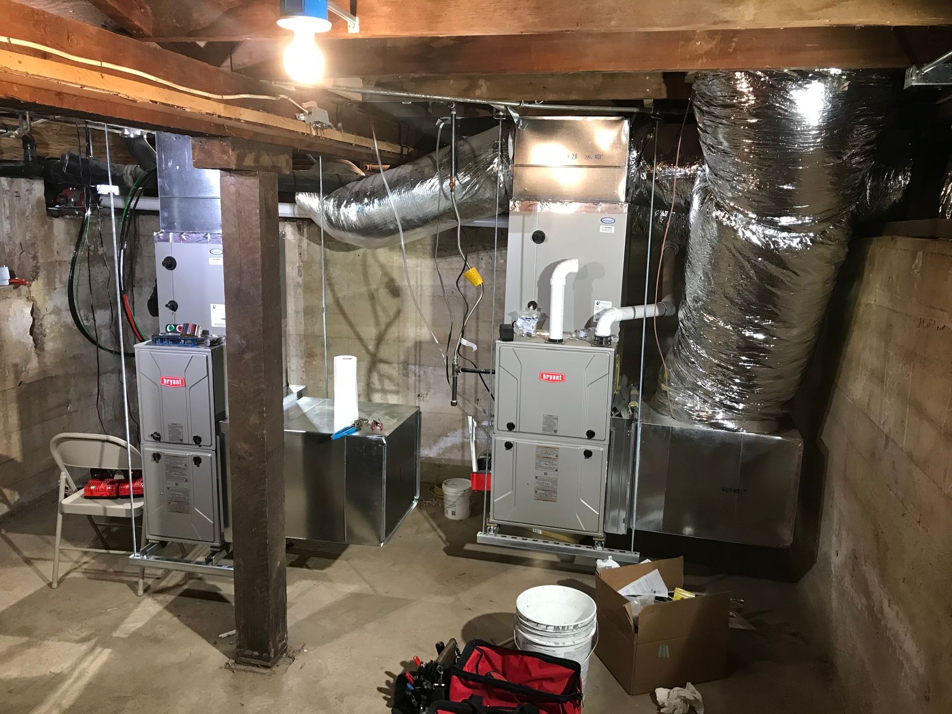 A basement with a lot of ducts and heaters.
