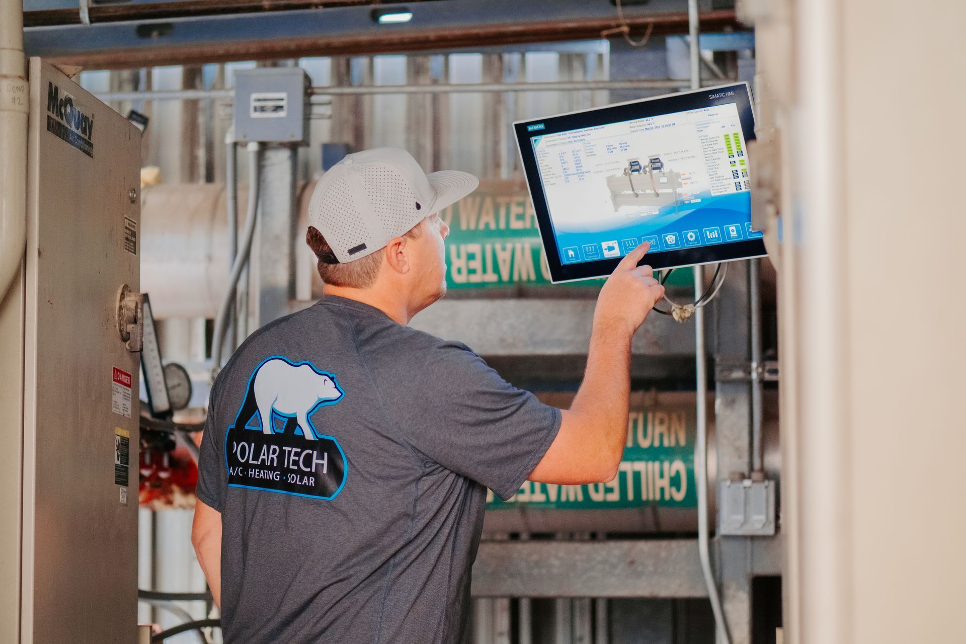 A woman is adjusting a thermostat with a smart phone.