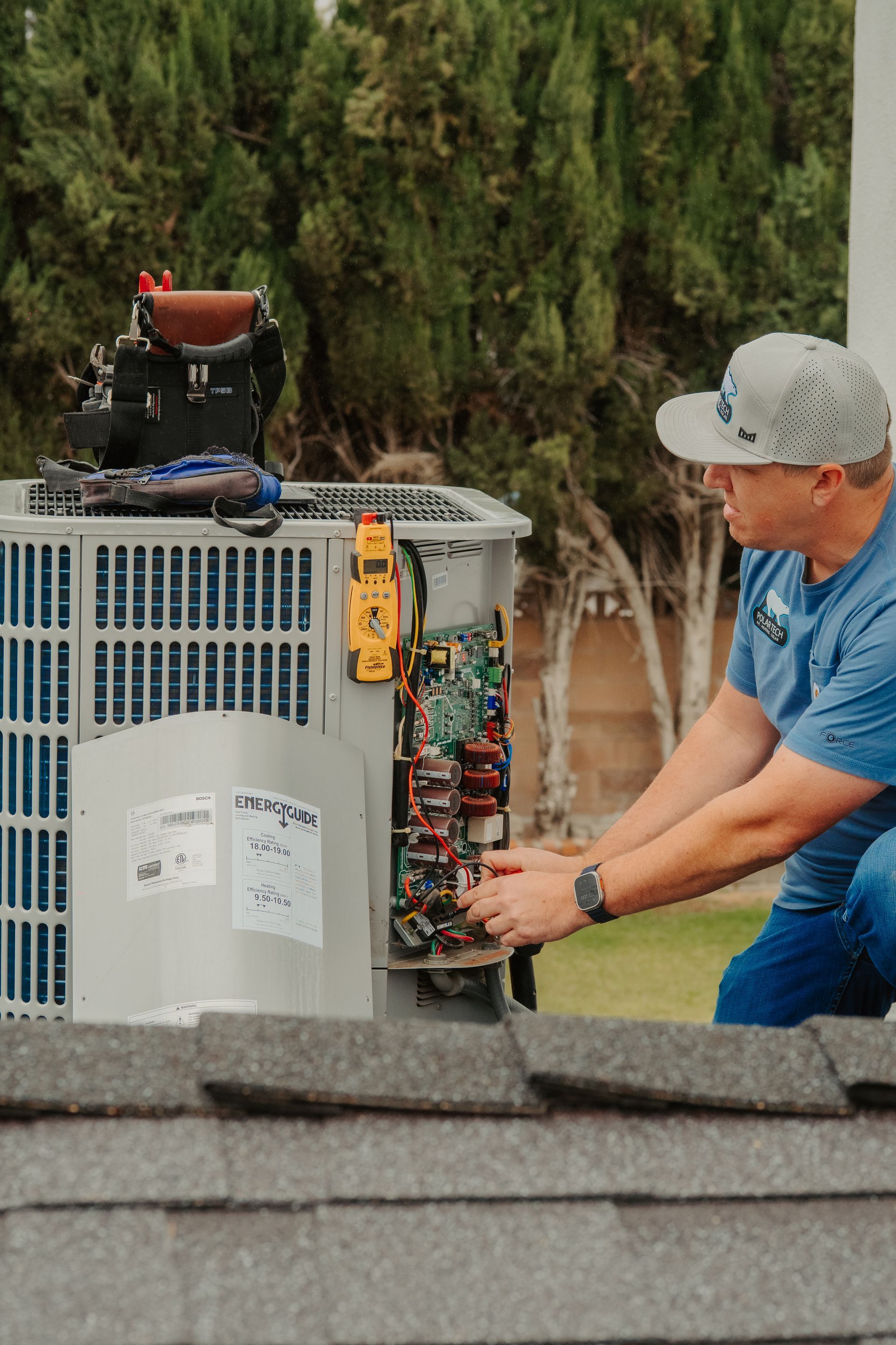 Two men are working on an air conditioner outside of a building.
