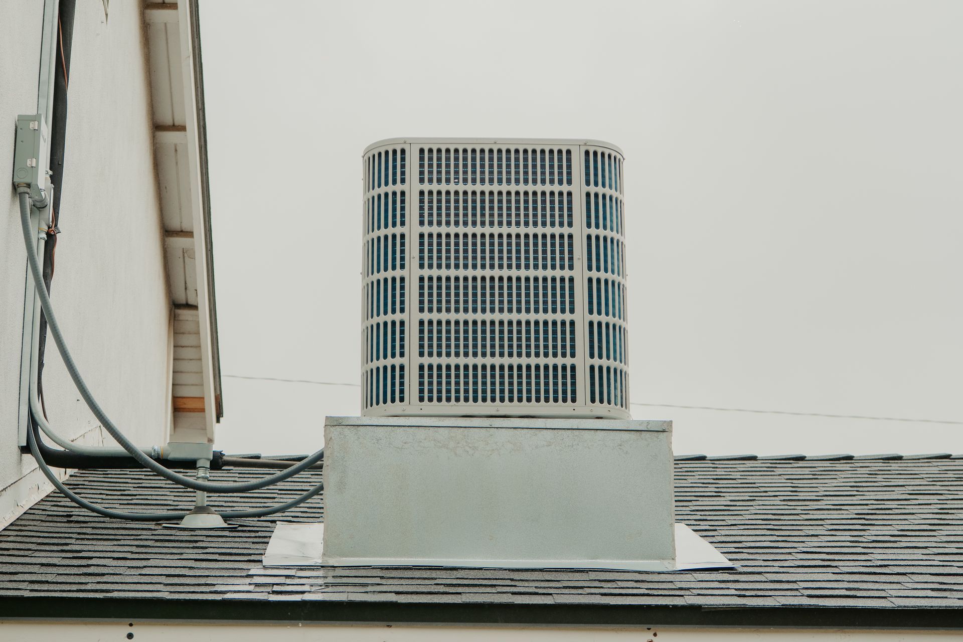 Two air conditioners are sitting on the side of a house.