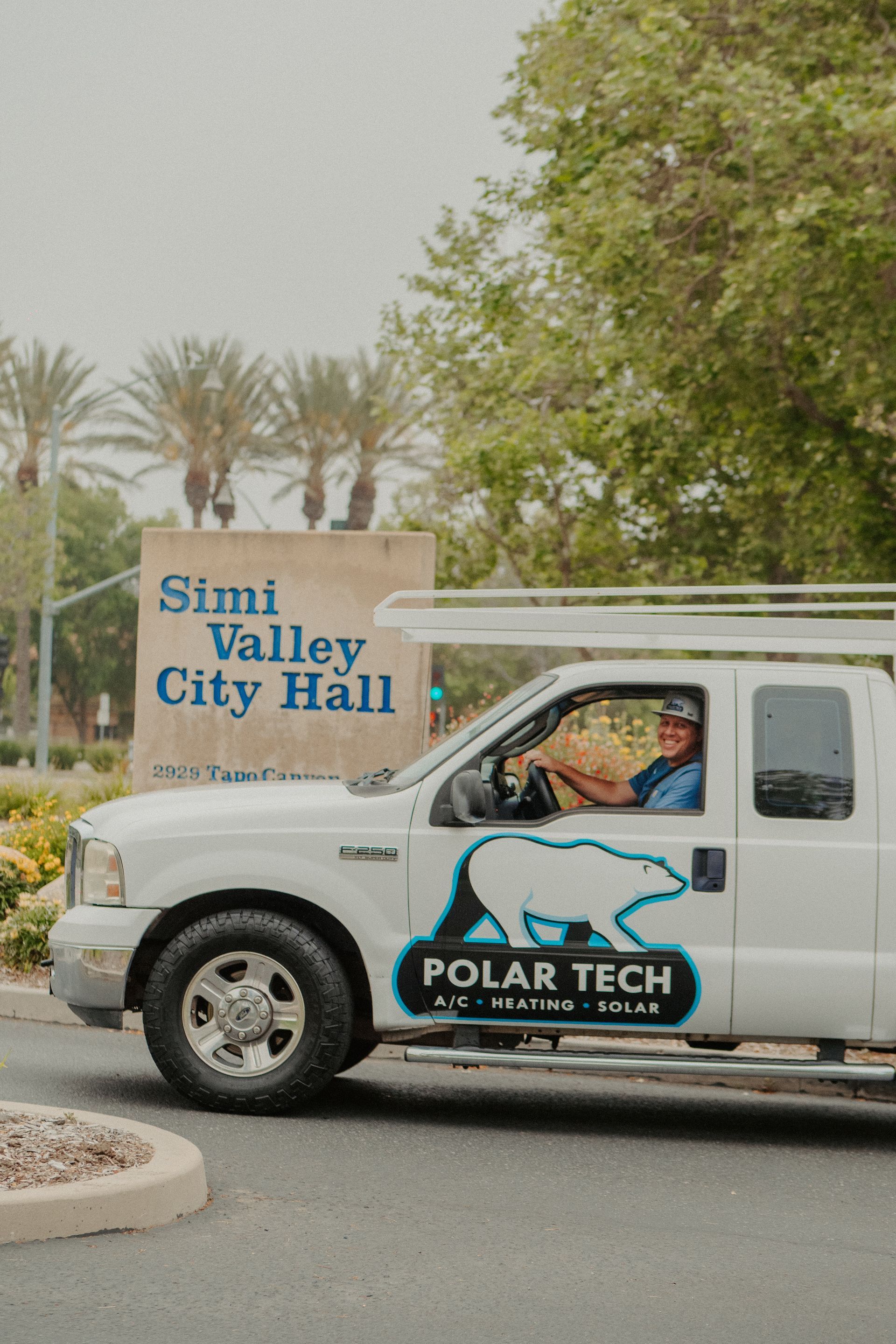 A man is working on an air conditioner while looking at a tablet.