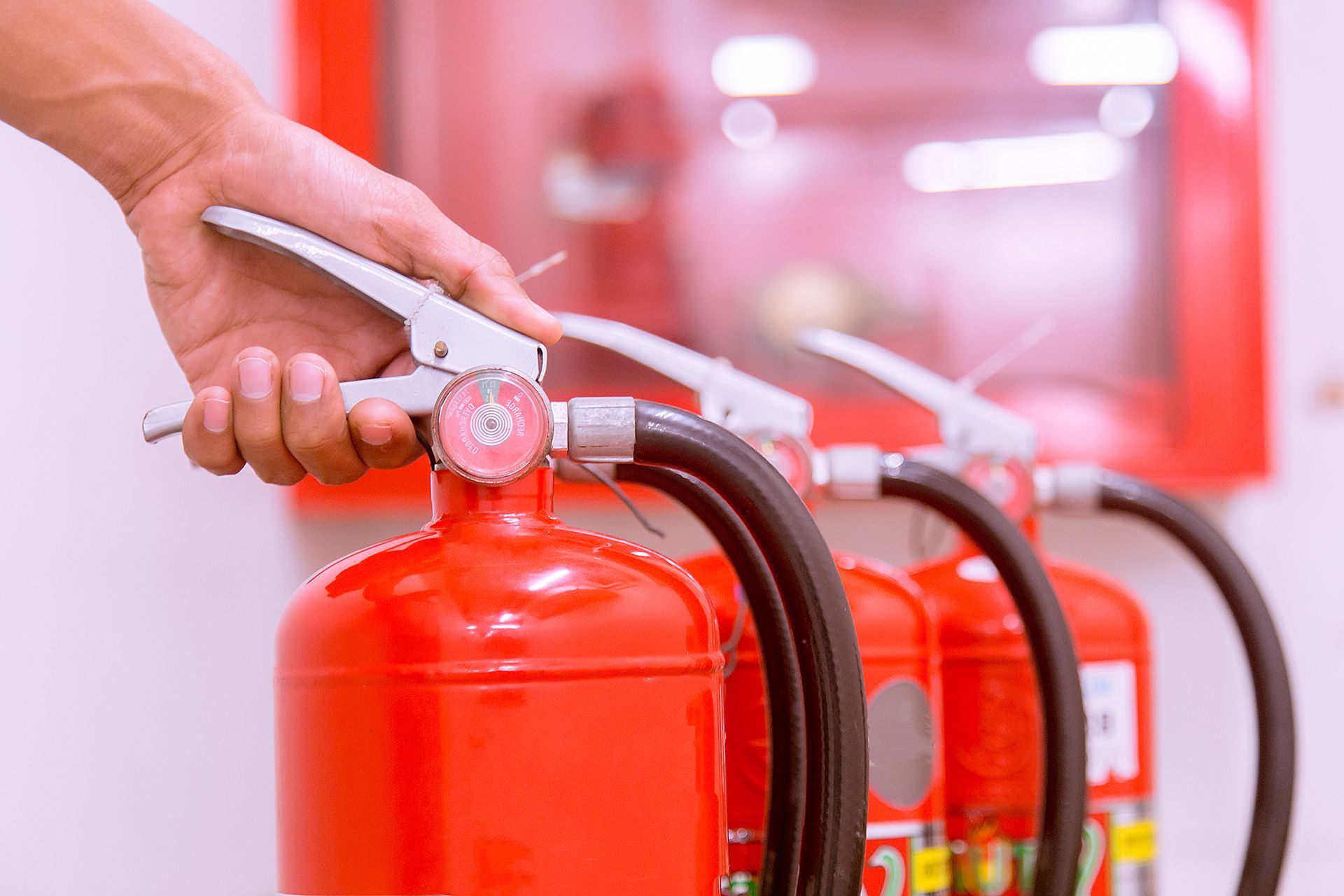 Una persona sostiene un extintor de incendios frente a una fila de extintores.
