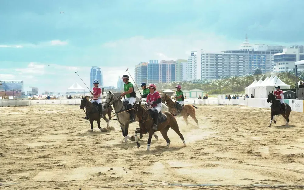 A group of people are riding horses on a sandy field.