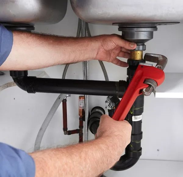 A Man Is Fixing A Sink With A Wrench — Malouf Plumbing In Pie Creek, QLD