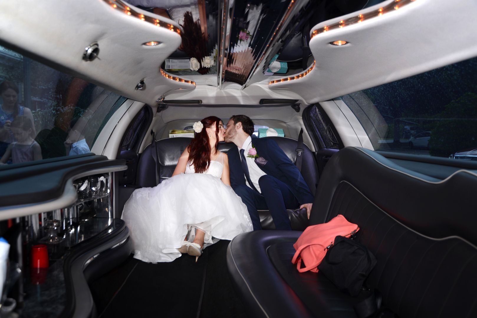 Bride and groom kiss in the back of a limousine after their wedding.