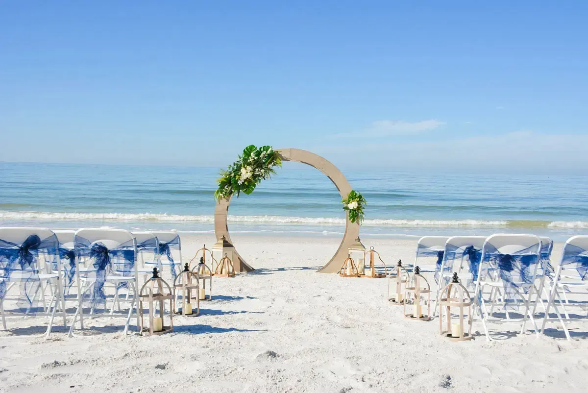 Beach wedding ceremony setup with an arch and chairs facing the ocean.