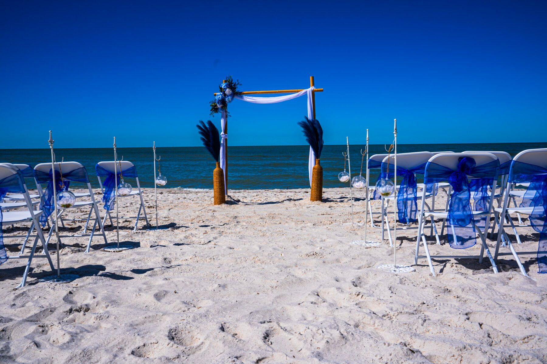 Beach wedding ceremony setup with blue accents and ocean backdrop.