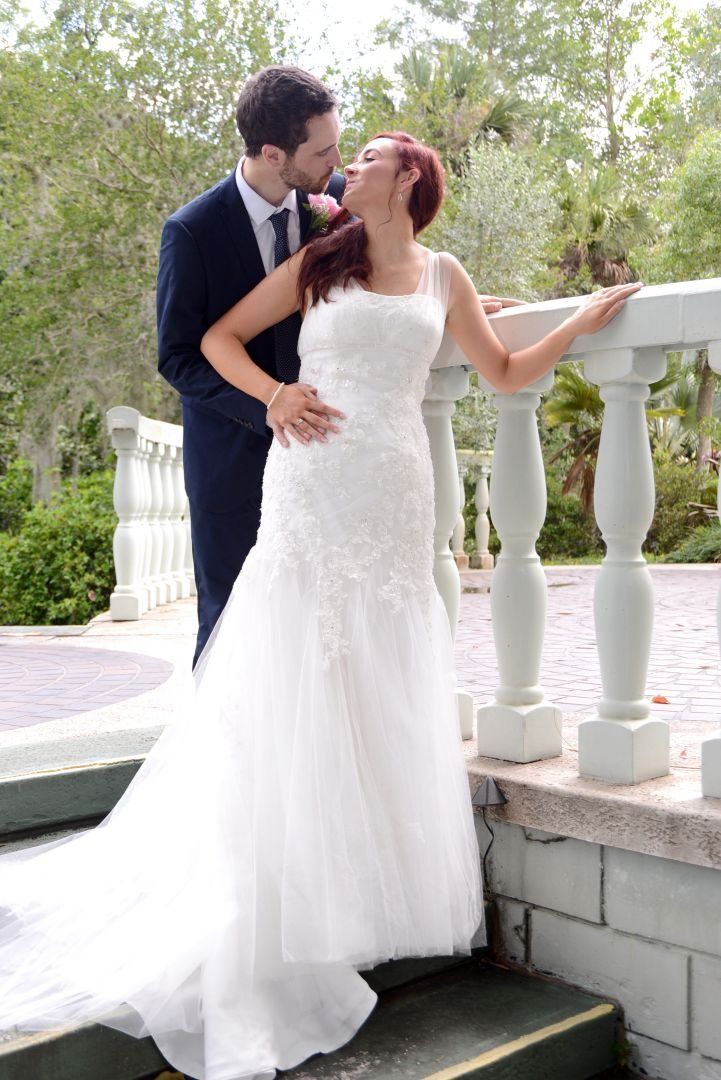 Couple kissing on a stone bridge; bride in white gown, groom in navy suit.