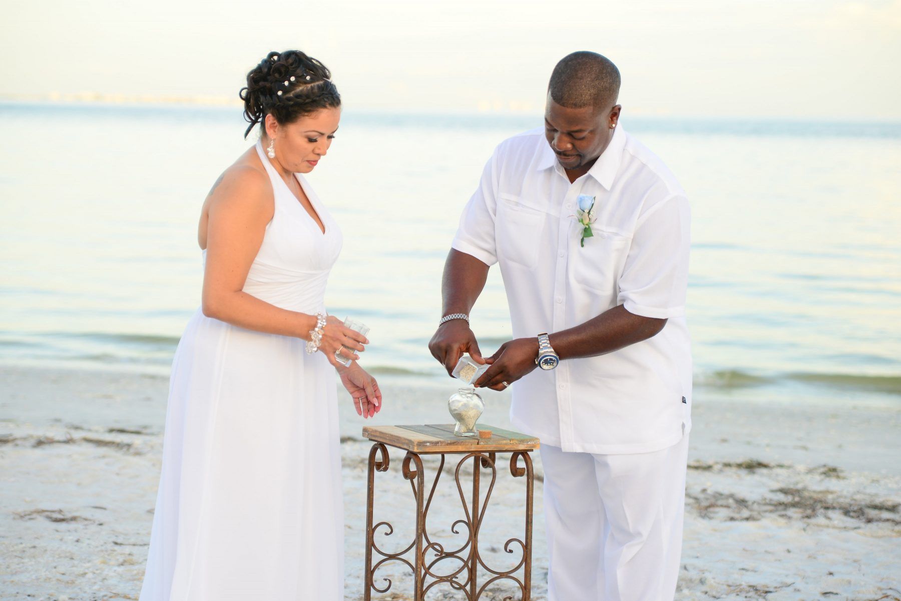 Couple pouring sand together at a beach wedding ceremony.