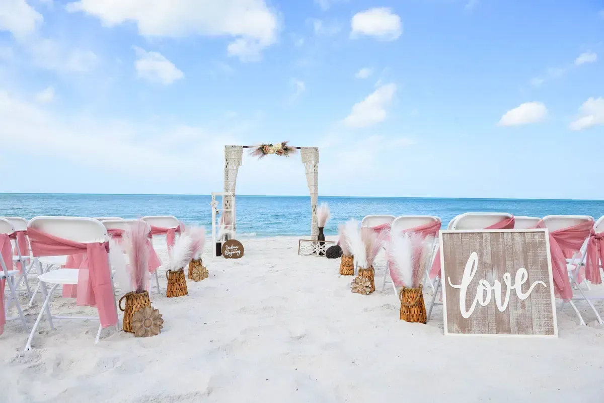 Beach wedding setup with chairs, arch, and 