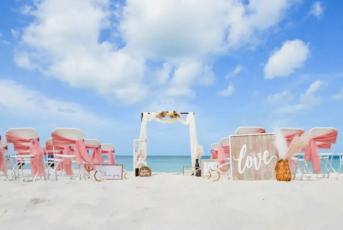 Beach wedding setup with chairs, arch, and 