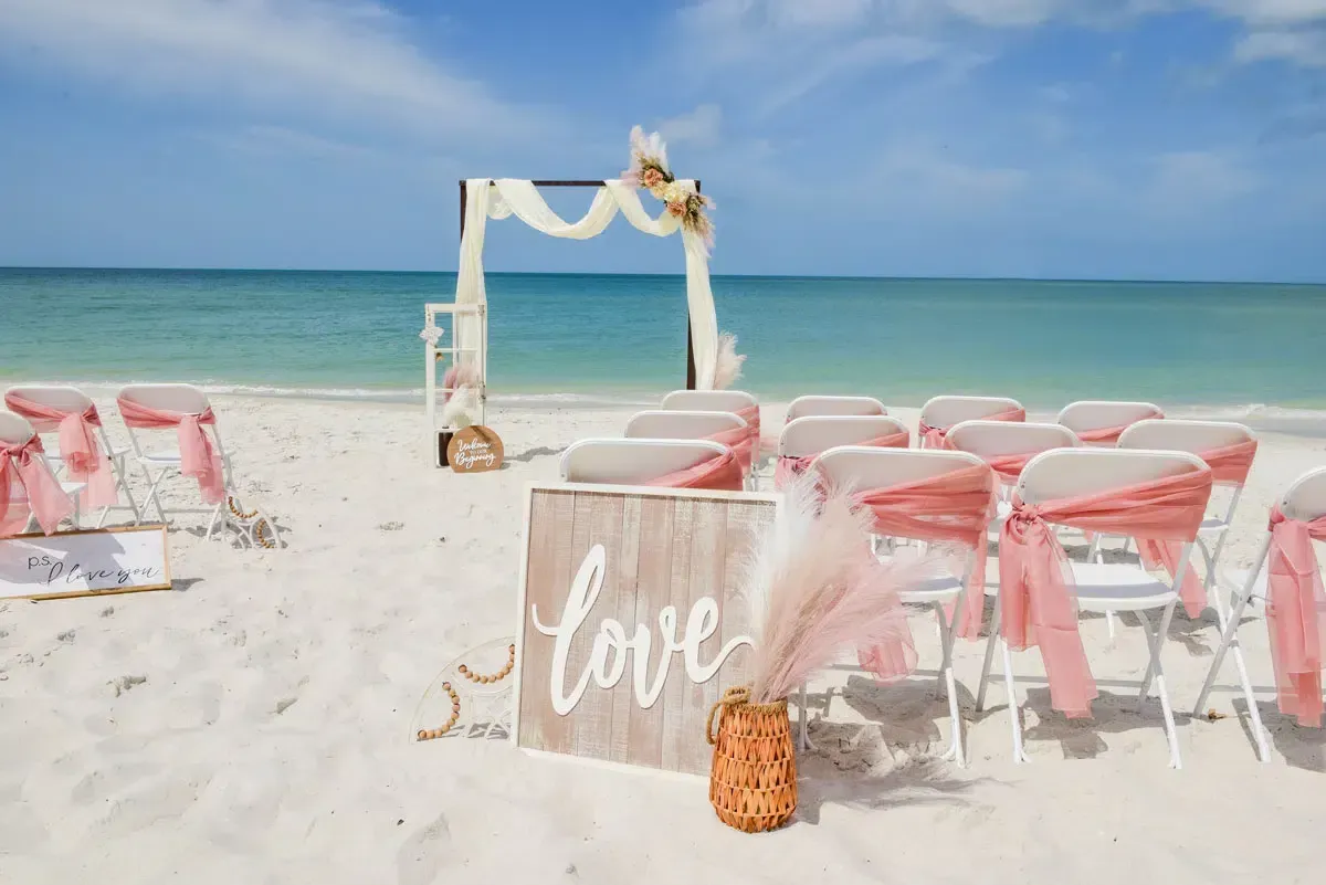 Beach wedding setup with chairs, arch, and 