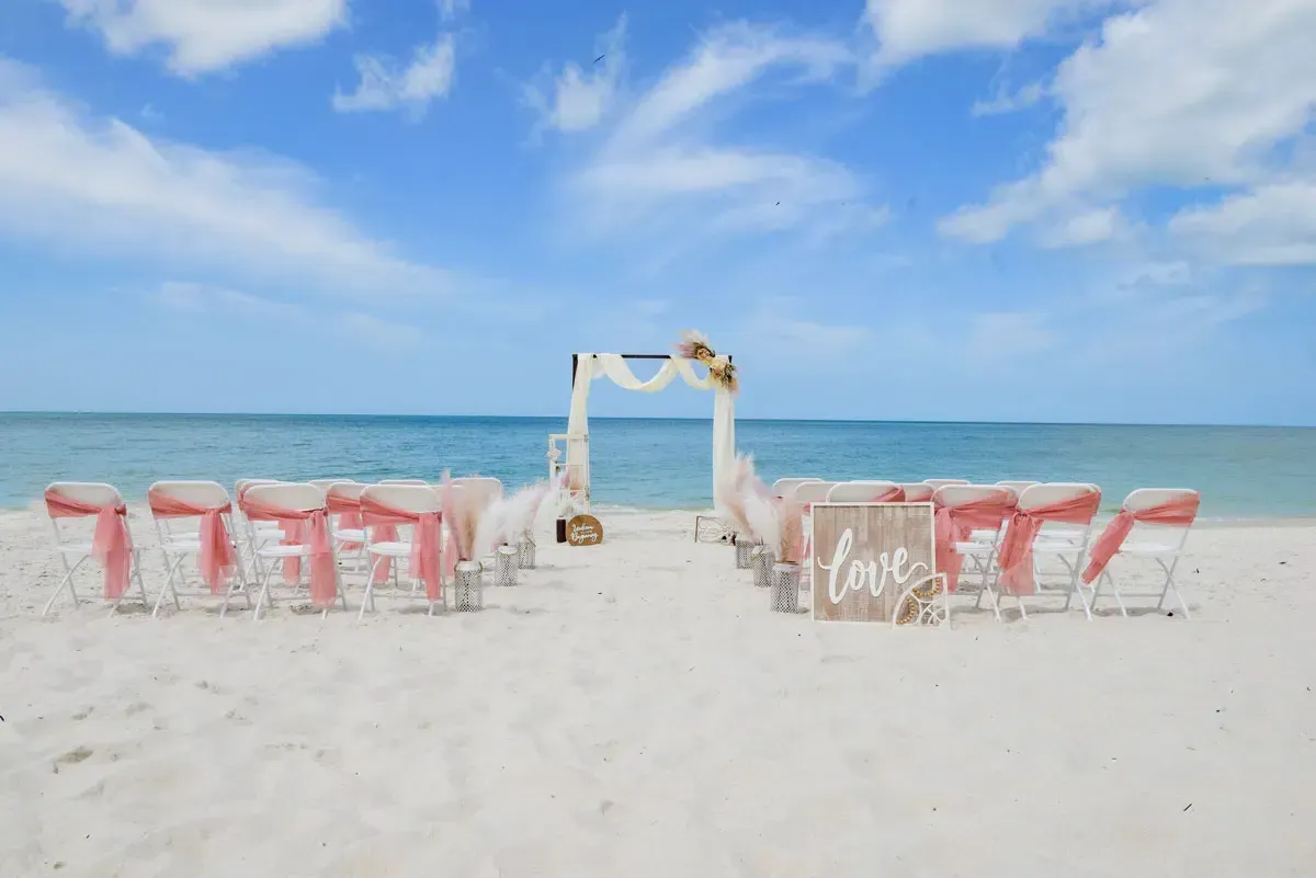 Beach wedding setup with chairs, arch, and 