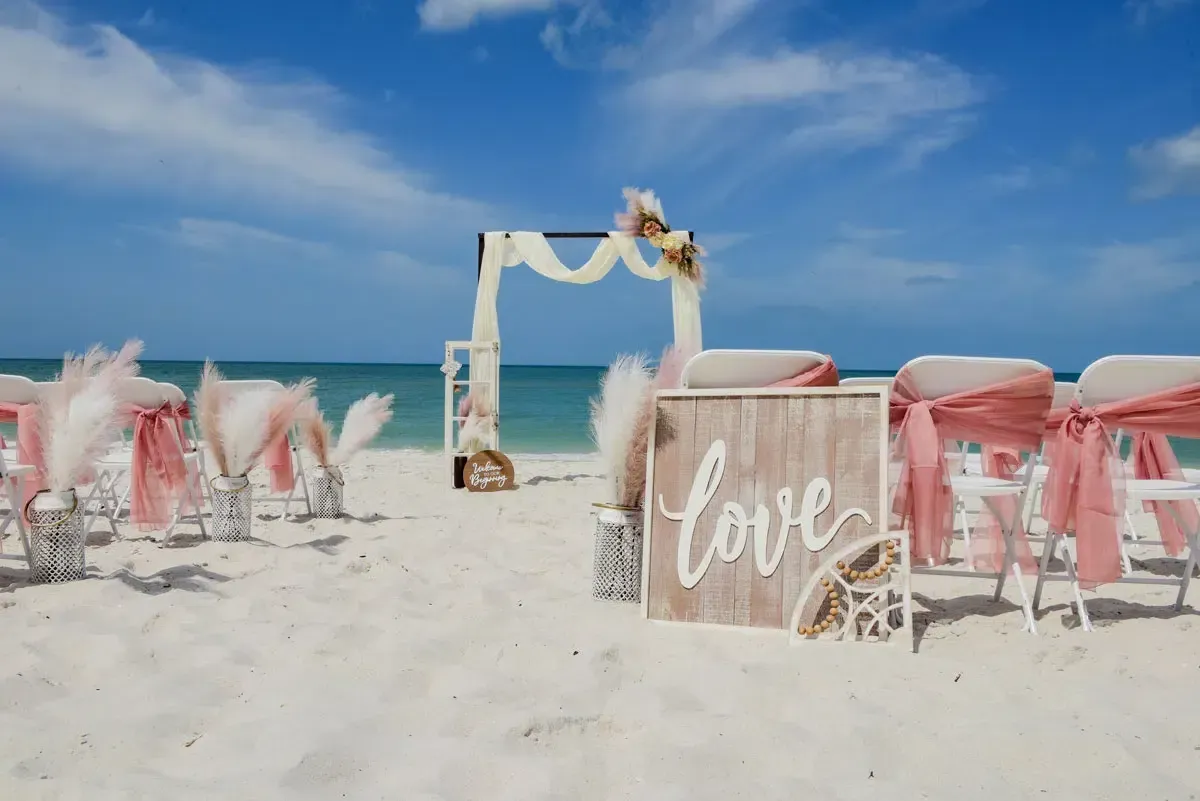 Beach wedding setup with chairs, an arch, and 