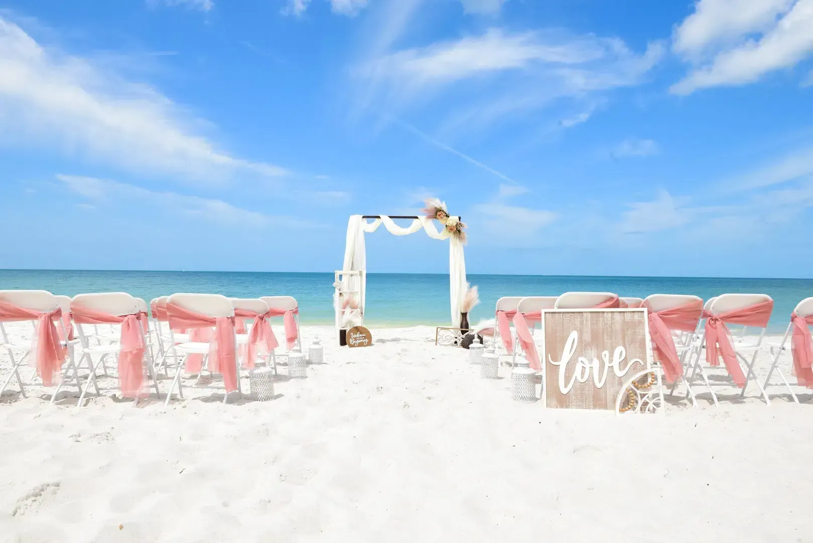 Beach wedding setup with chairs, arch, and 