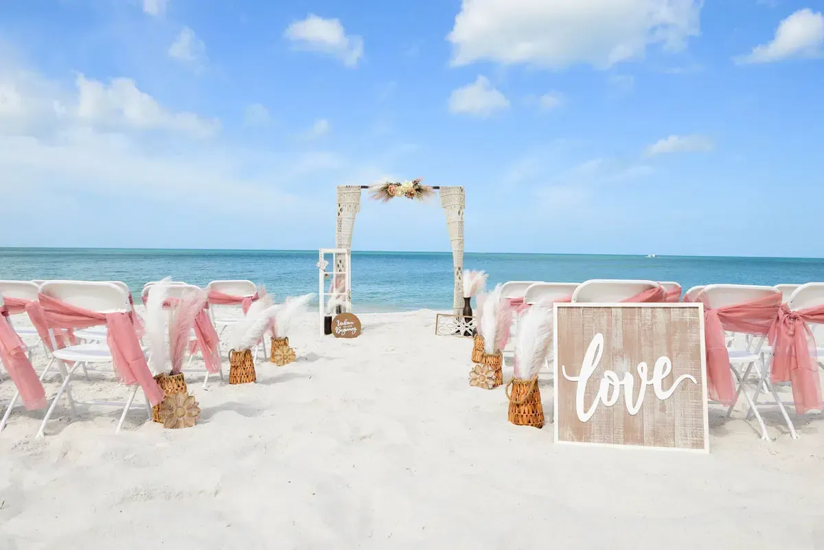 Beach wedding setup with arch, chairs, and 