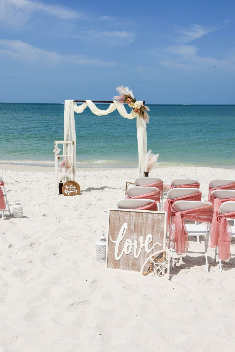 Beach wedding setup with arch, chairs, and 