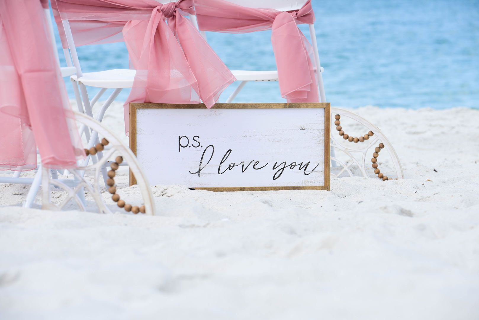 White wooden sign on sand: 