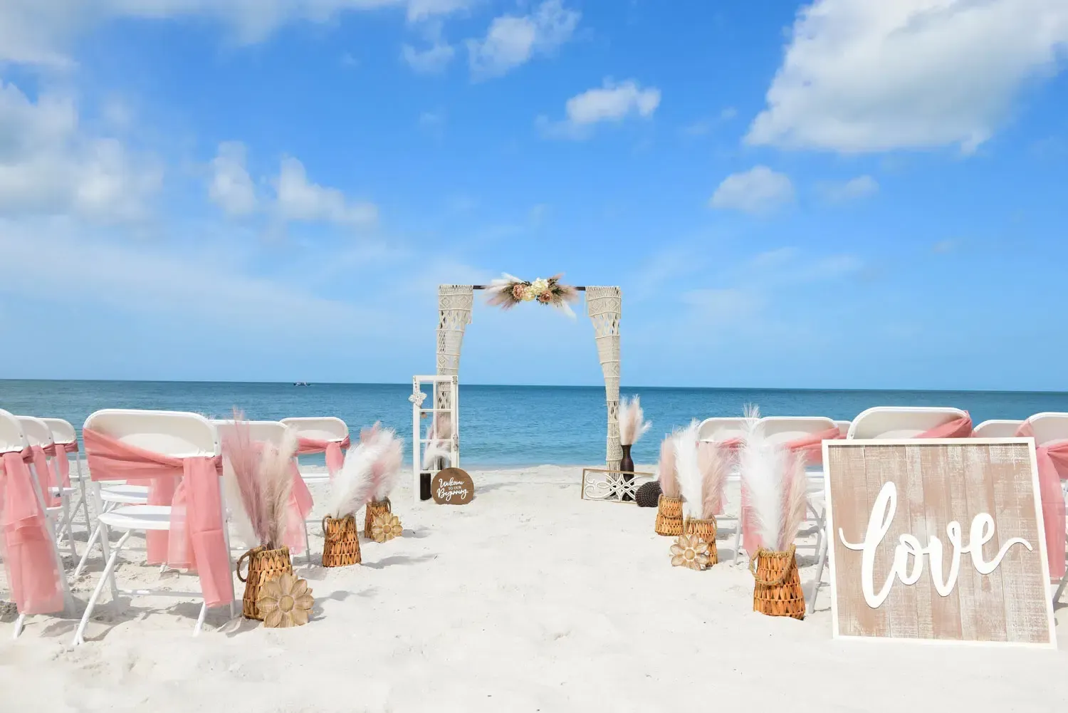 Beach wedding ceremony setup with pink accents and 