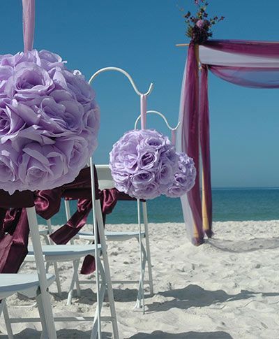 Purple flowers are hanging from a pole on the beach