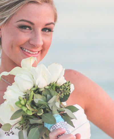 A woman in a white dress is holding a bouquet of white flowers