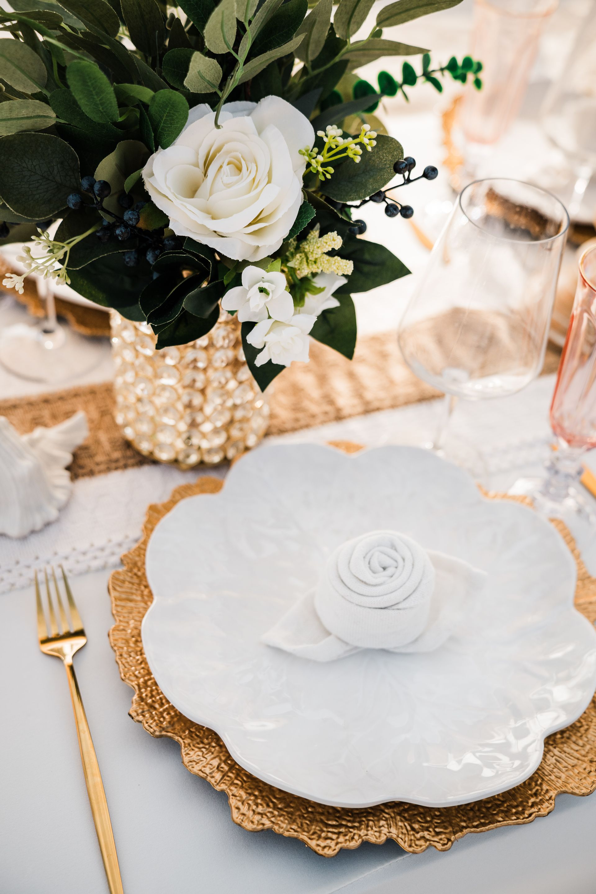 Elegant table setting with white flower centerpiece and gold accents.