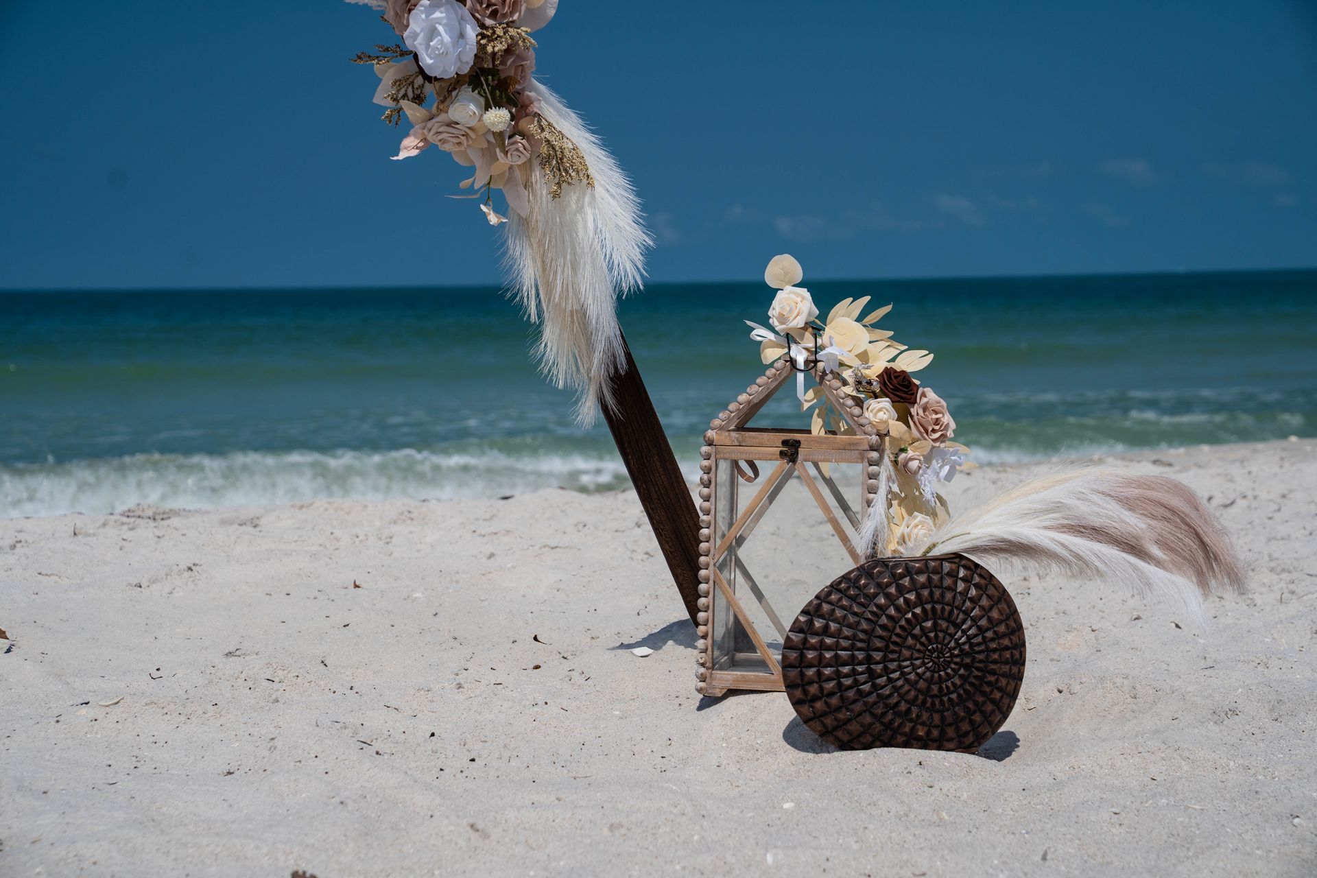 Wedding decorations on a sandy beach with the ocean in the background.