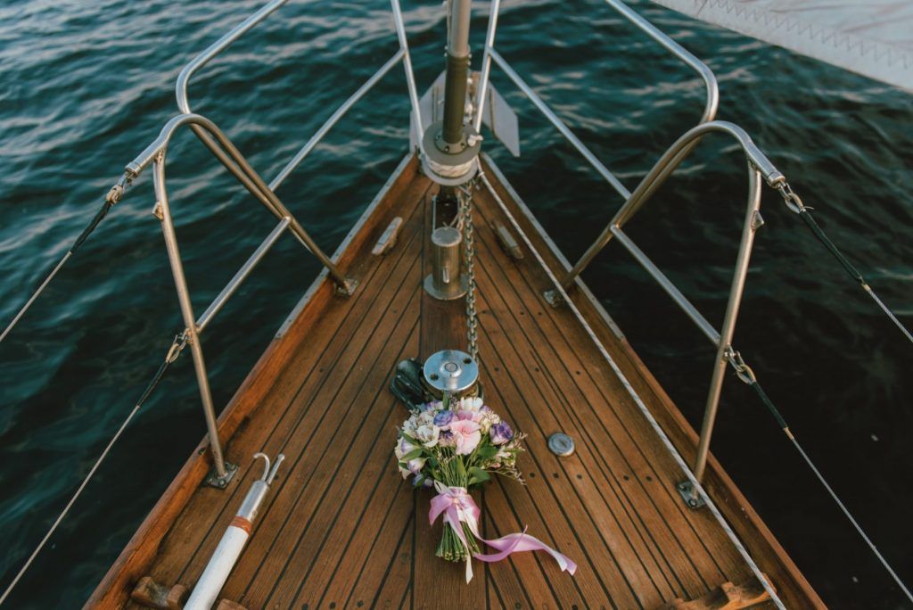 Bouquet on the bow of a wooden sailboat, with a dark blue ocean in the background.