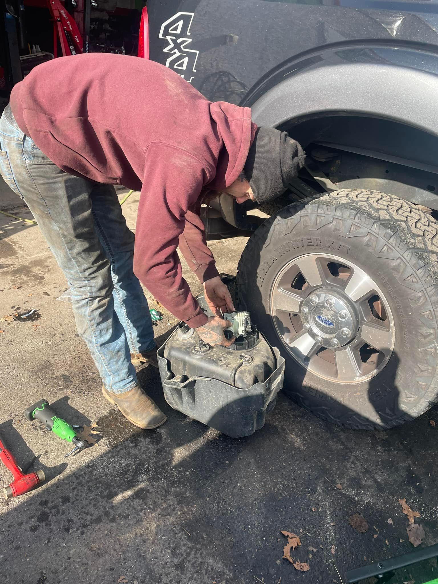 A man is bending over to fix a tire on a truck.