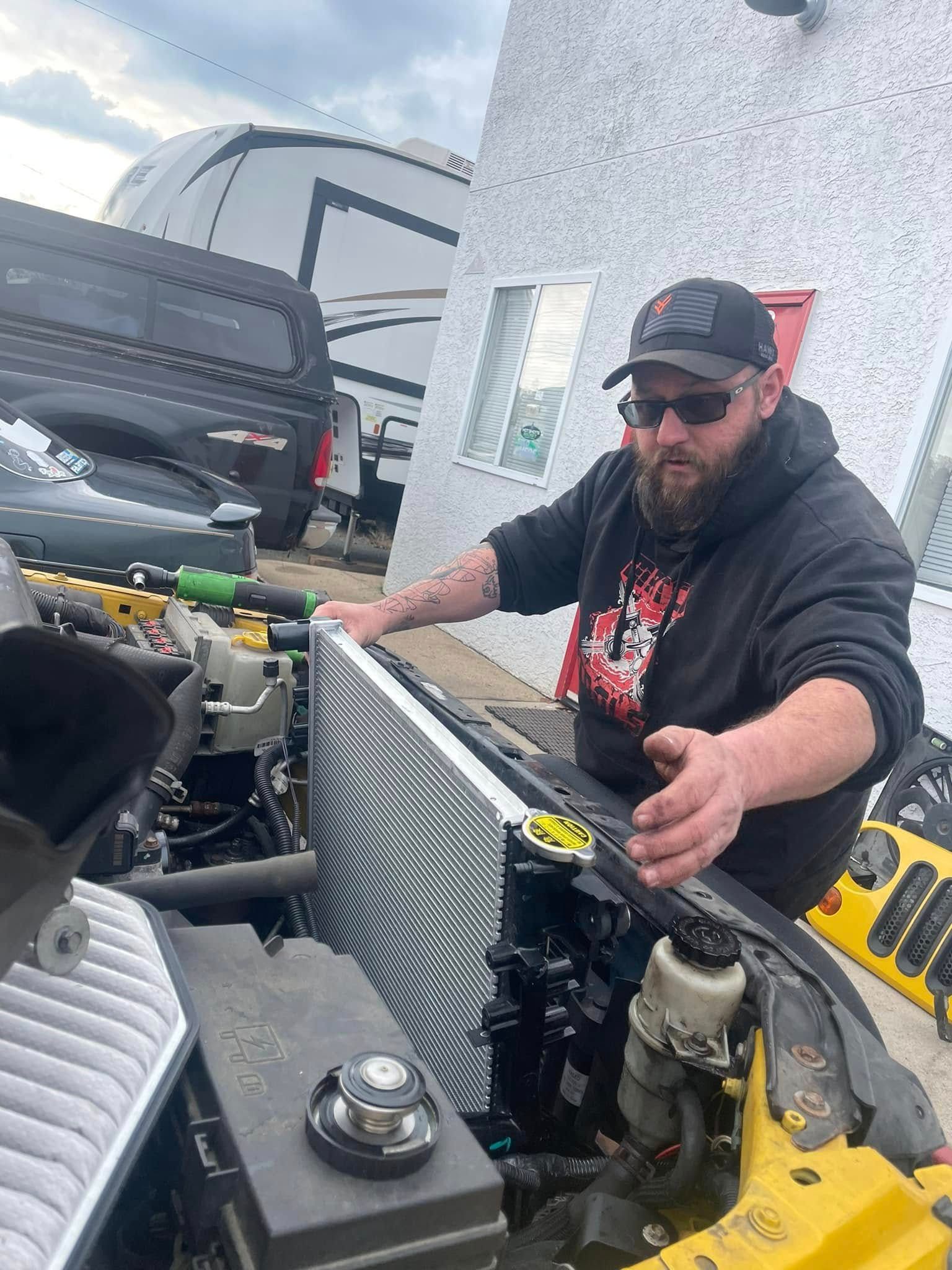 A man is working on the radiator of a car.